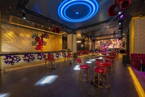A bar area with red stools and a stage with a large screen.