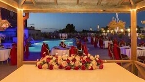 An outdoor dining area with tables set for a meal, overlooking a pool and a night sky. - Wyndham Istanbul Old City (Istanbul)