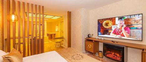 A hotel room with a bed, a television, a fireplace, and a wooden partition.