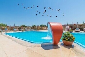 Uma piscina com estrutura curva e um vaso de planta.