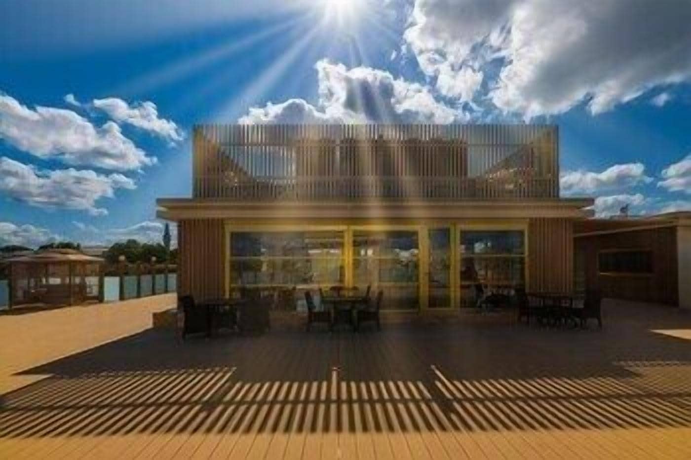 A modern building with a wooden deck, large windows, and a clear sky.