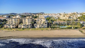 A coastal residential area with multi-story buildings, a beach, and ocean waves.