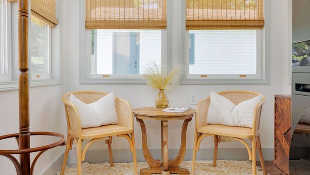 A room with two wicker chairs, a round wooden table, and a vase with dried plants. - Welcome to Casa de Campo! Your Home Away From Home (Saint Joseph)
