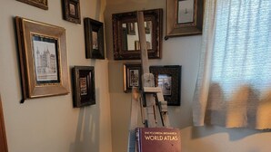 Une pièce dans laquelle se trouve un chevalet en bois, sur lequel est posé un livre intitulé « Encyclopédie Britannica, atlas du monde ».