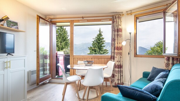 Een gezellige kamer met een eettafel, stoelen, een bank en een televisie.