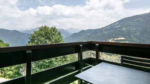 Een balkon met een tafel en uitzicht op een bergachtig landschap.