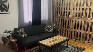 A living room with a sofa, coffee table, and a wooden partition. - Historic Mt. Iron Apartment (Mountain Iron)
