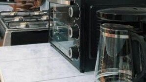 Una cocina con armarios de madera, estufa, cafetera y salpicadero de azulejos.
