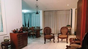 Amplia sala de estar con comedor, que incluye un mueble grande de madera, dos sillones, una mesita y una lámpara en el techo.