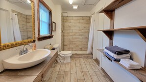 A bathroom with a large mirror, a sink, a toilet, and a shower area. - Cozy private cottage only 2 miles to downtown & ATT center  (San Antonio)