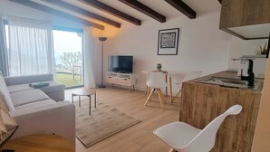 Un soggiorno moderno con un divano, una TV e un'area pranzo con sedie e tavolo.