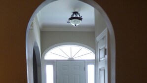 A hallway with a white door, a ceiling fan, and a wooden floor.