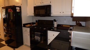 A kitchen with white cabinets, a black refrigerator, a microwave, a stove, and a dishwasher.