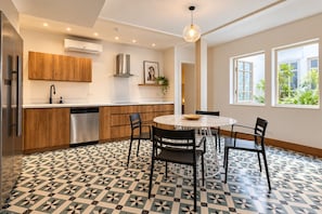 A modern kitchen with wooden cabinets, a stainless steel dishwasher, and a round dining table with chairs. - Beautiful and spacious 3 bedrooms in the Old Town with balcony (Ciudad de Panamá)