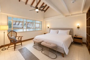 Une chambre à coucher avec un grand lit, une chaise, une table de chevet, une lampe et une fenêtre donnant sur un beau paysage.