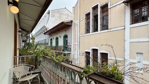 A balcony with a wooden railing, a white chair, and potted plants. - Beautiful and spacious 3 bedrooms in the Old Town with balcony (Ciudad de Panamá)