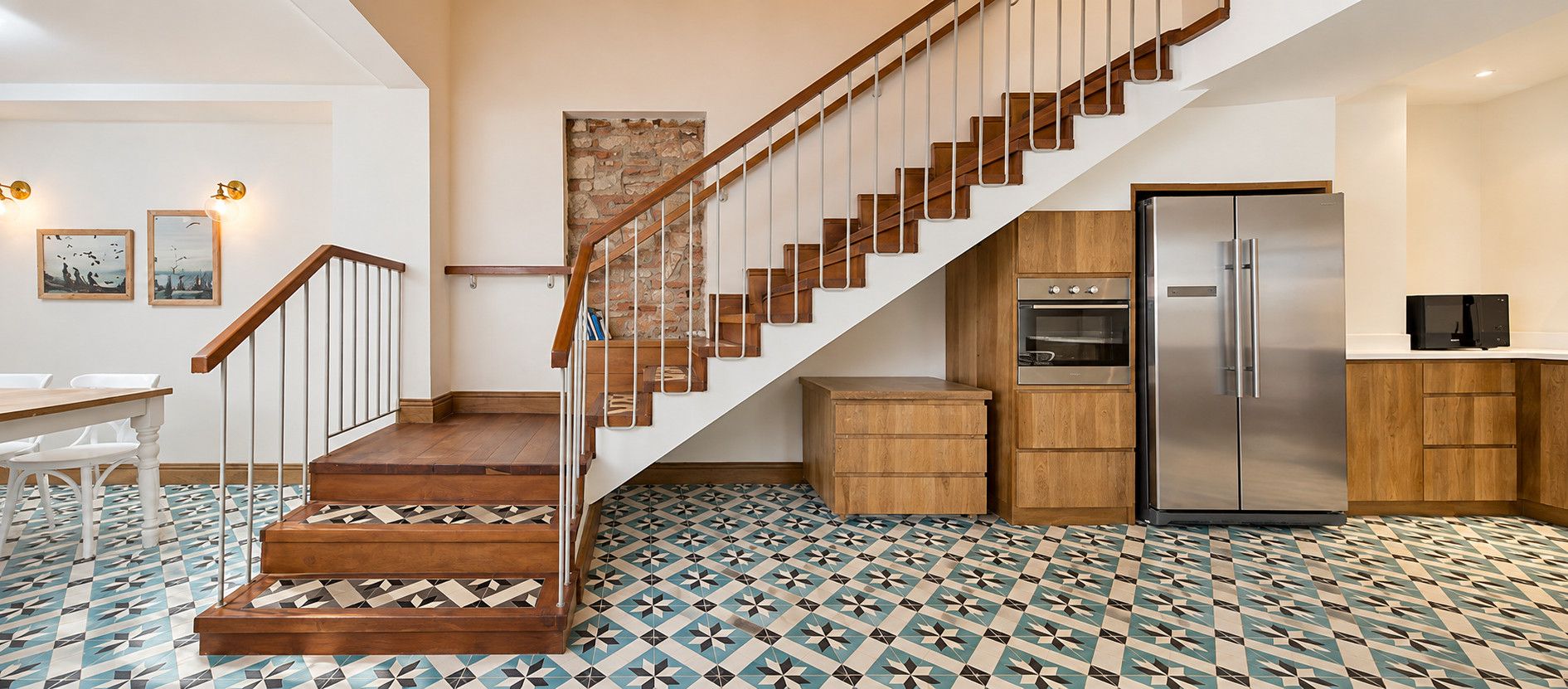 Eine Küche mit einer Holztreppe, einem Kühlschrank und einem Fliesenboden.