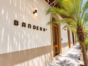 A building with a sign reading 'BANDERA' and a palm tree in the foreground. - Beautiful and spacious 3 bedrooms in the Old Town with balcony (Ciudad de Panamá)