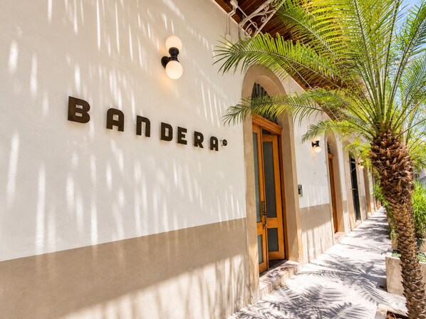 Un edificio con un letrero que dice 'BANDERA' y una palmera en primer plano.