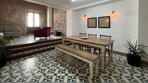 A dining area with a wooden table and chairs, a bench, a sofa, and a stone wall. - Beautiful and spacious 3 bedrooms in the Old Town with balcony (Ciudad de Panamá)