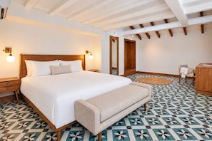 A hotel room with a large bed, bedside tables, a bench, a desk, and a patterned floor. - Rooftop Private Terrace + Spacious 1BR @CascoViejo (Ciudad de Panamá)
