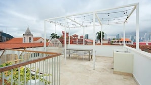 A rooftop terrace with a white pergola, string lights, a table, and a sink. - Rooftop Private Terrace + Spacious 1BR @CascoViejo (Ciudad de Panamá)