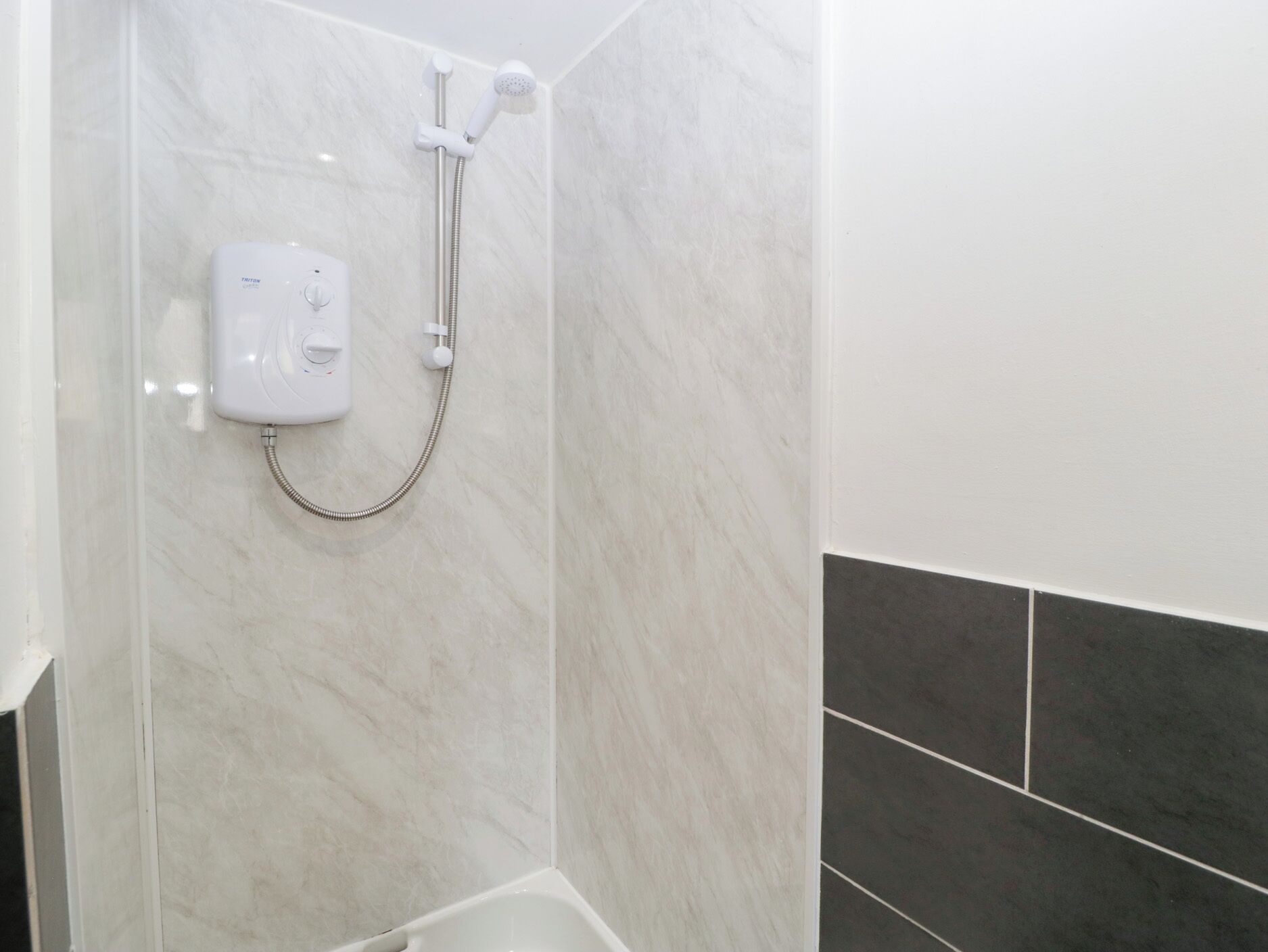 A bathroom with a shower, a handheld showerhead, and a handheld shower attachment.