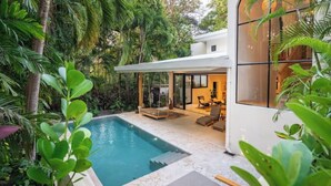 Une maison moderne dotée d’une piscine, le tout entouré d’une végétation luxuriante.