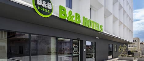 Un hotel B&B con fachada moderna, amplios ventanales de vidrio y un cielo despejado.