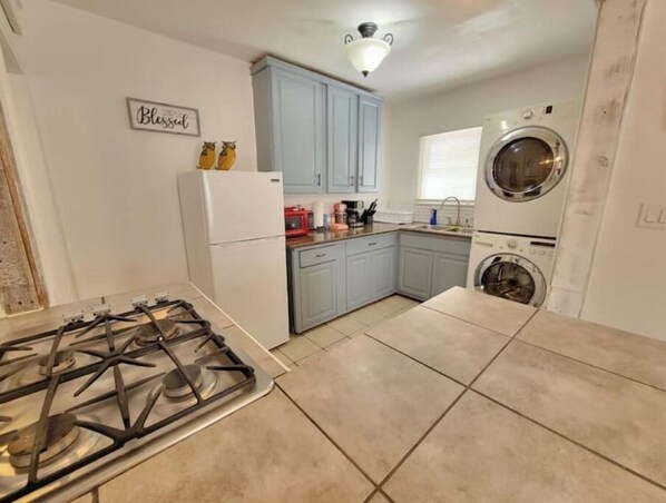 A compact kitchen with a gas stove, a washing machine, and light blue cabinets. - Relaxing KING bed & 2 queen beds 1 mile to Downtown Riverwalk (San Antonio)
