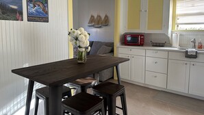A kitchen with white cabinets, a red microwave, and a vase of flowers on the table. - Downtown Snoqualmie Home - Hot Tub, Fully Fenced Yard - Pet Friendly! (Snoqualmie)