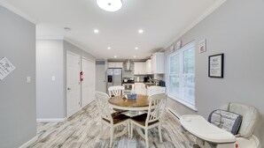 Una cocina moderna con armarios blancos, una mesa de comedor de madera con sillas y una trona para bebé.