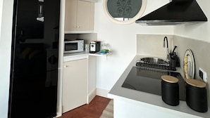 A compact kitchen with a black refrigerator, microwave, and stove, white cabinets, and a small sink. - Modern and bright apartment located on the Catania waterfront. (Catania)