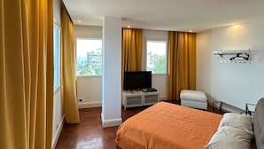 A modern bedroom with a large bed, a TV on a white cabinet, and a window with curtains. - Modern and bright apartment located on the Catania waterfront. (Catania)