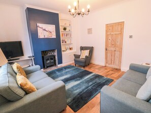 A living room with a fireplace, a television, a bookshelf, and a door.