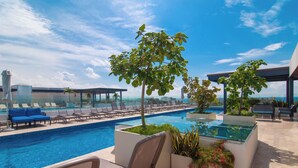 A rooftop pool area with lounge chairs, a glass-enclosed pool, and potted plants. - Ipana by Casago (Playa del Carmen)