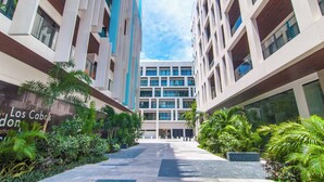 A modern building with a central atrium, surrounded by lush greenery and a clear sky. - Ipana by Casago (Playa del Carmen)