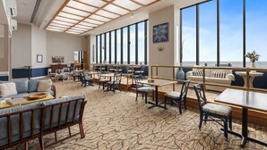 A spacious indoor area with a patterned carpet, wooden furniture, and large windows offering a view.