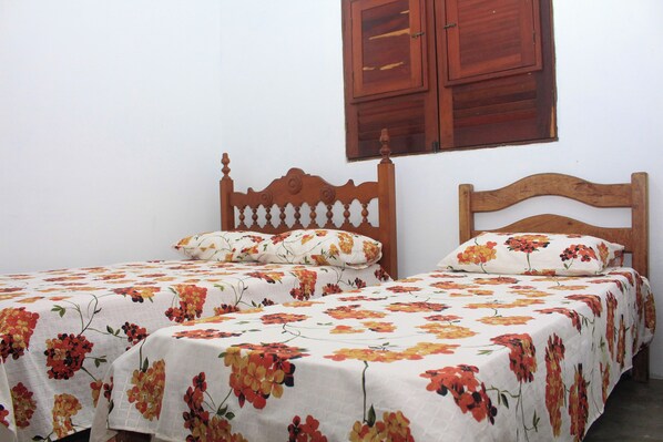 Une chambre avec deux lits simples, chacun doté d’une tête de lit en bois et d’une literie à motifs floraux.