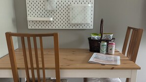 A dining table with two wooden chairs, a pegboard wall, and a basket with beverages. - The Hyde Park Hideaway | Centrally-Located | Cozy (Austin)