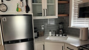 A kitchen with a stainless steel refrigerator, white cabinets, a microwave, and a stove. - The Hyde Park Hideaway | Centrally-Located | Cozy (Austin)