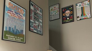 A staircase with wooden steps and a white handrail, leading to a landing where four event posters are displayed on the wall. - The Hyde Park Hideaway | Centrally-Located | Cozy (Austin)