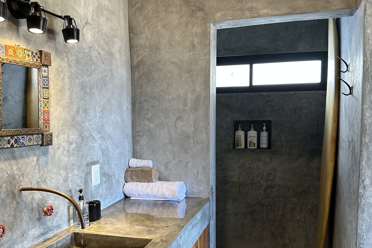 A bathroom with a large mirror, a sink, and a shower area.