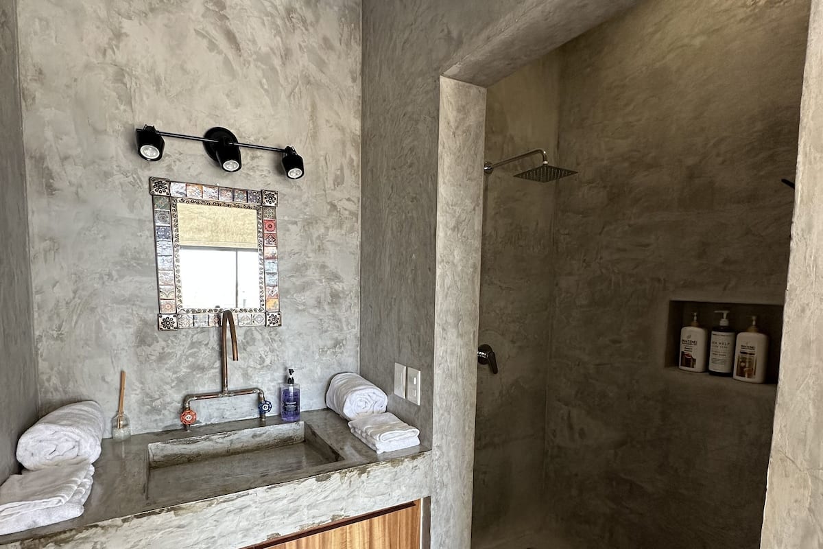 A bathroom with a marble sink, wooden cabinets, a mirror with a decorative frame, and a shower area.
