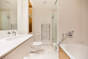 Features a sleek design with a large mirror, separate toilet, and walk-in shower.