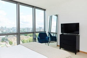 Enjoy a panoramic city view from the comfort of this stylish room, featuring a large bed, flat-screen TV, and comfortable seating area.