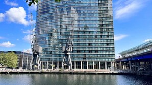 Un bâtiment moderne à la façade incurvée et aux grandes fenêtres, situé au bord d’un plan d’eau.
