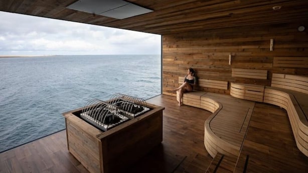 Interior de madera con vista al mar, una parrilla empotrada y una zona de estar curvo.