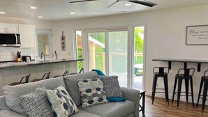 A modern living room with a grey sofa, a coffee table, and a ceiling fan. - GOTL - Hot Tub - Wine Tours - Sunset Vacation Rentals (Geneva)