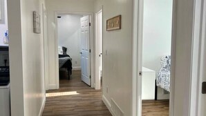 A hallway with wooden flooring, white walls, and doors leading to bedrooms. - GOTL - Hot Tub - Wine Tours - Sunset Vacation Rentals (Geneva)